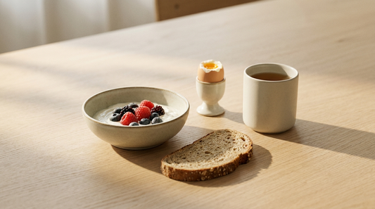Frühstückstisch im Morgenlicht mit Quark und Beeren, Vollkornbrot, gekochtem Ei und einer Tasse Tee